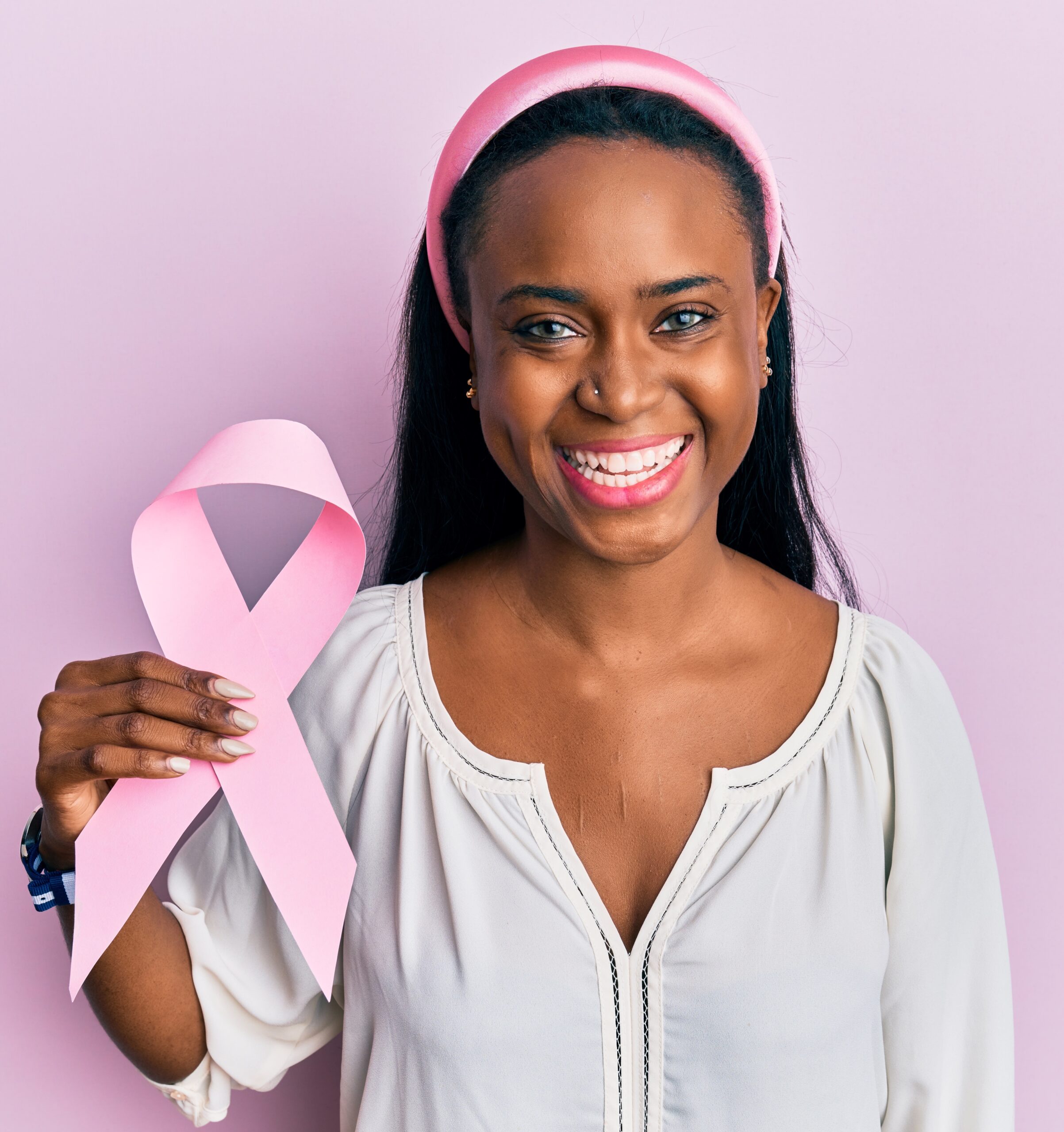 Young african woman holding pink cancer ribbon looking positive and happy standing and smiling with a confident smile
